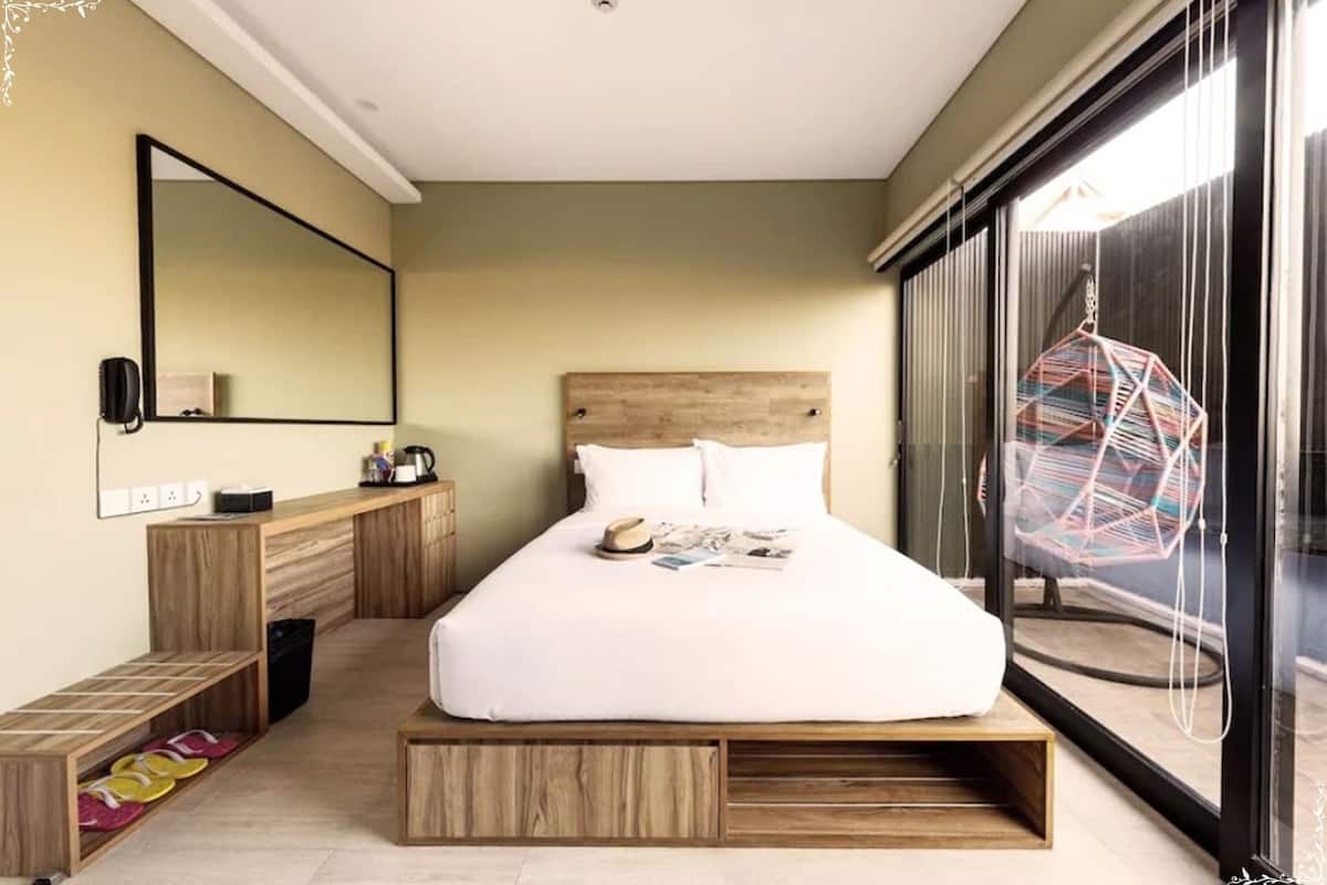 A modern bedroom with a large bed, wooden headboard, built-in storage, a large mirror, and a view of the outdoors.
