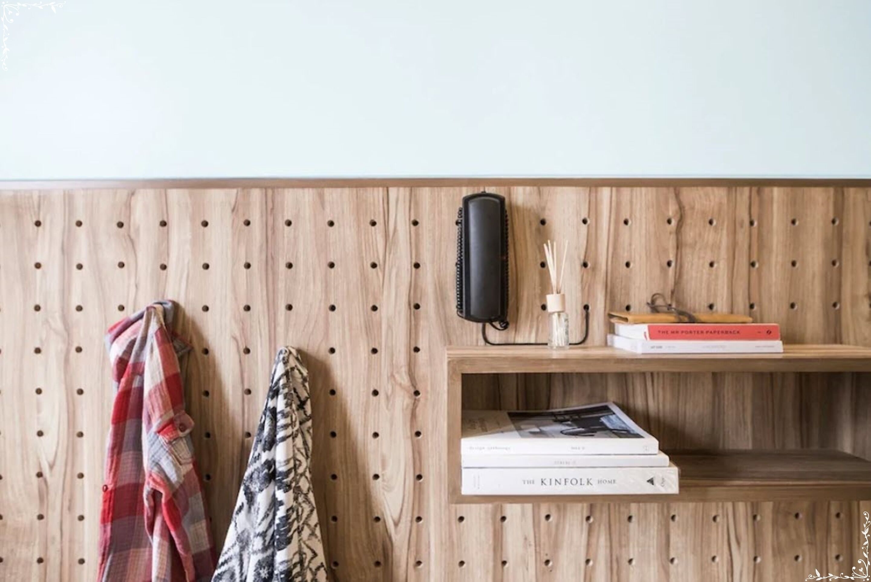 A wooden wall with a pegboard, a shelf with books, a black speaker, and a scarf.