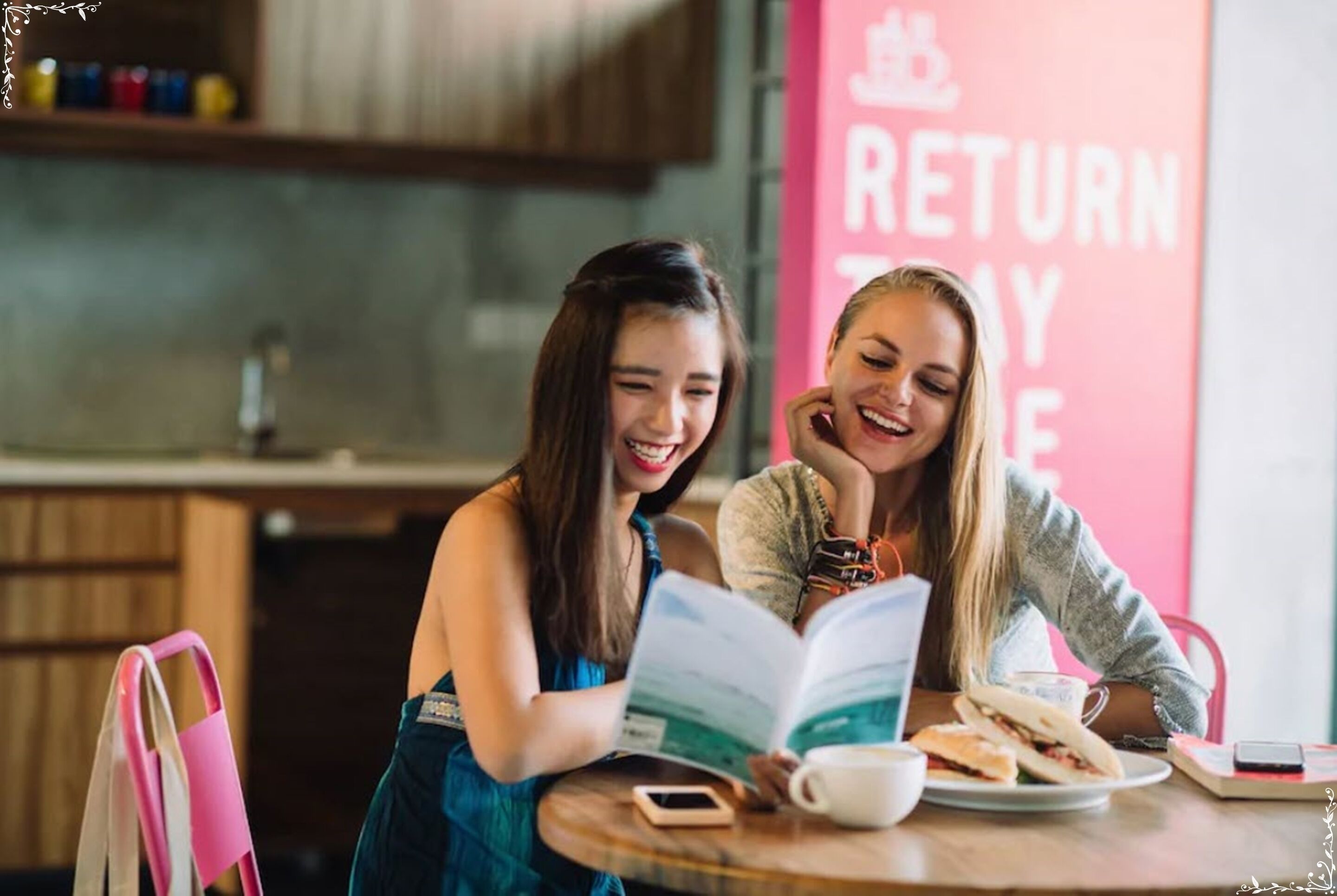 Two people sitting at a table with a book and a cup, in a room with a 'RETURN TO YOUR' sign.