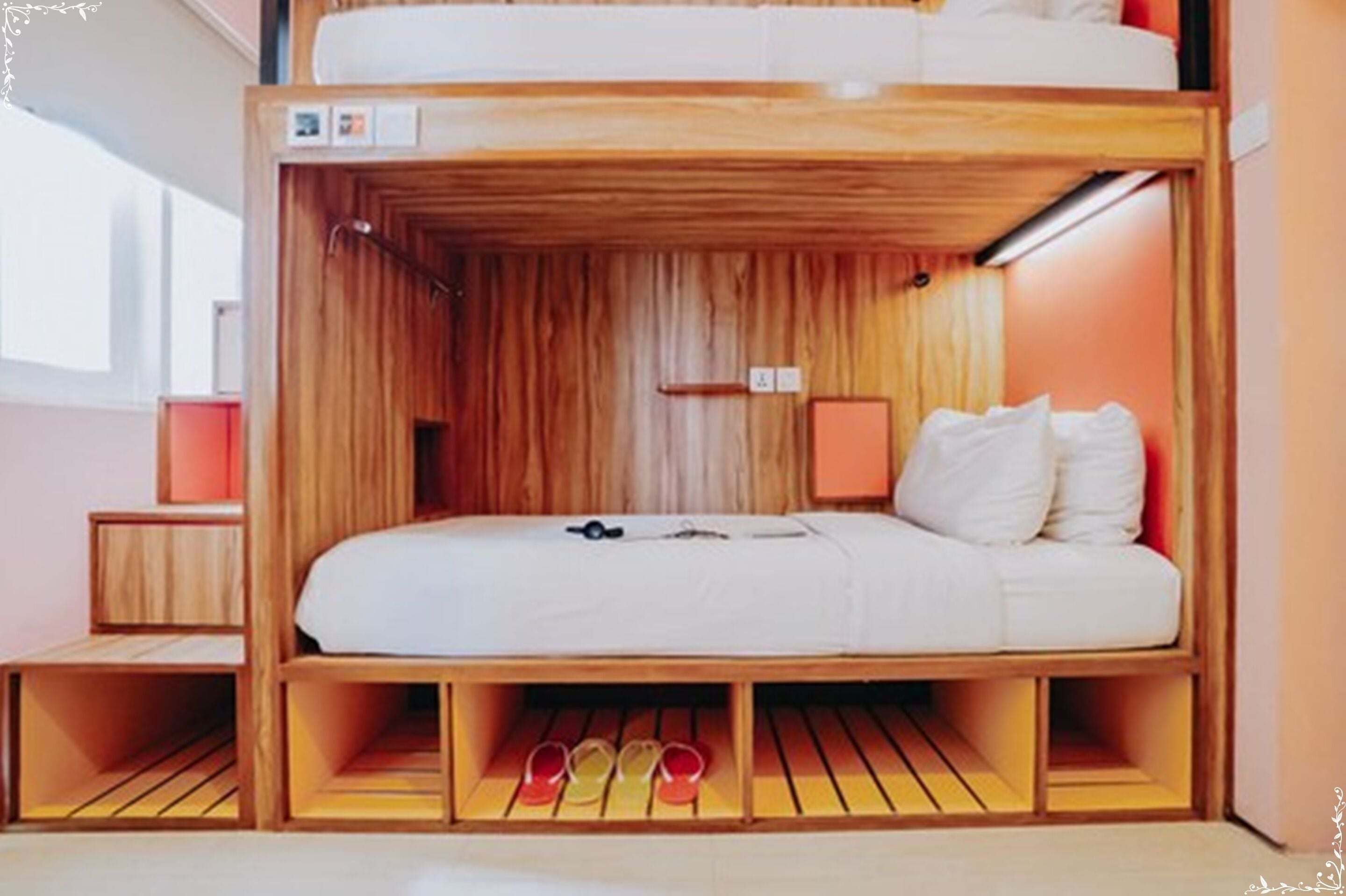 A bunk bed room with a wooden interior, a small bedside table, and a shelf with shoes.
