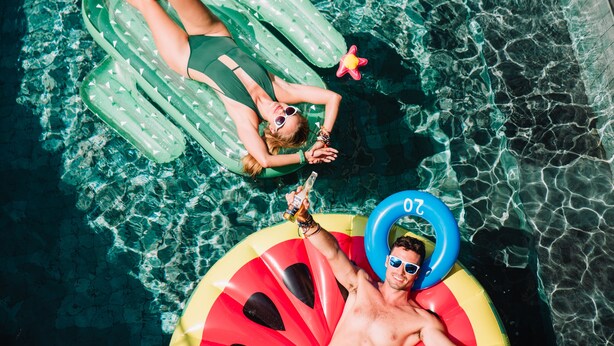 Two people floating on inflatable pools in a clear pool. - Cara Cara Inn (Kuta)