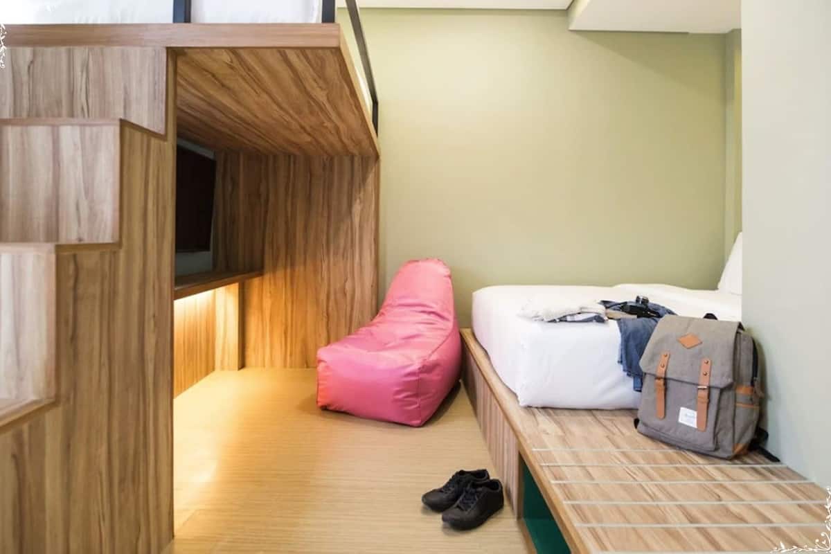 A compact room with a bunk bed, a pink bean bag, a backpack, and a pair of shoes on the floor.