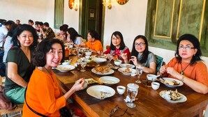 A group of people dining at a wooden table with various dishes and drinks.