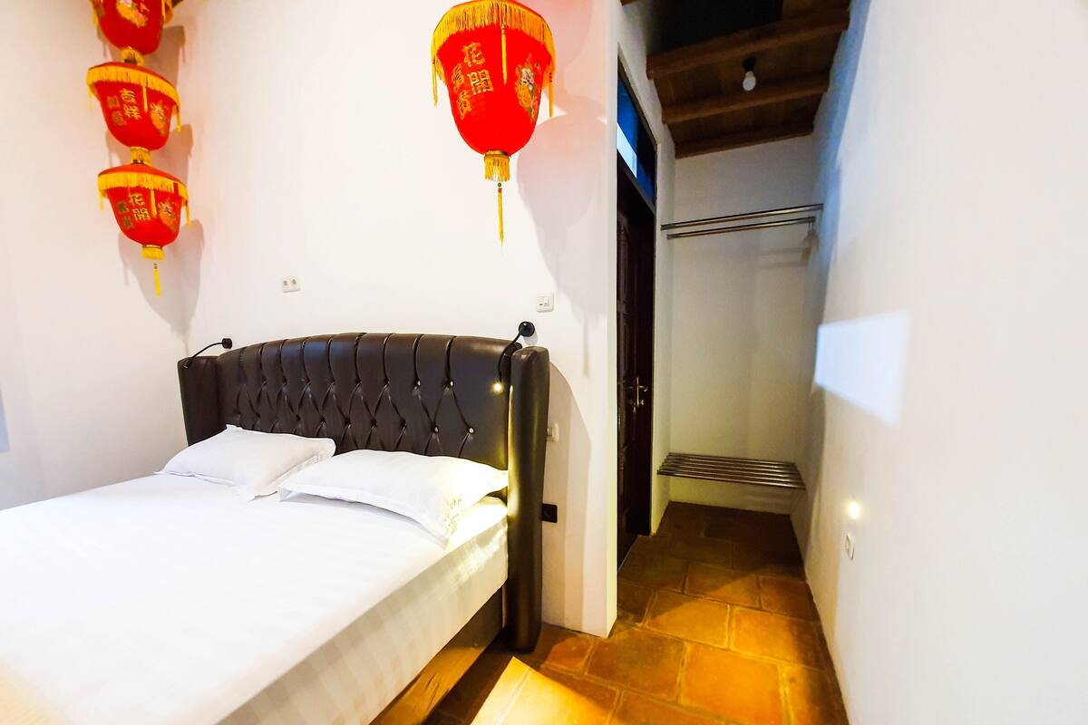 Een hotelkamer met een bed, een hoofdeinde en een rode lantaarn aan de muur.