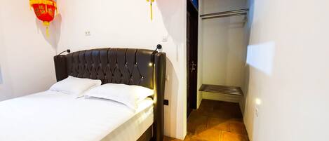 A hotel room with a bed, a headboard, and a wall-mounted red lantern.