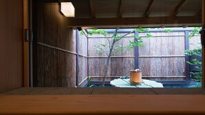 A wooden interior with a view of a bamboo fence and a tree outside.