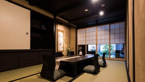 A traditional Japanese-style room with tatami flooring, a low table with cushions, and sliding shoji doors.