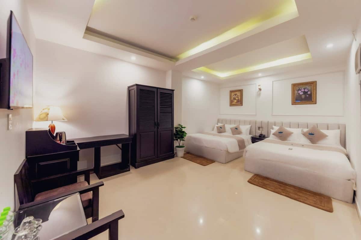 Une chambre d’hôtel avec un grand lit, un lit plus petit, un bureau, une armoire et un téléviseur.