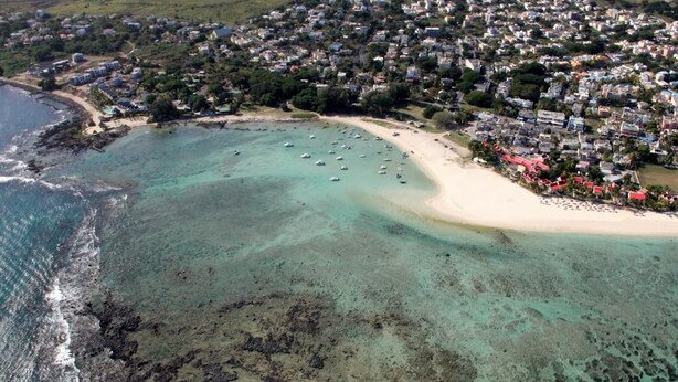 An aerial view of a coastal town with a beach, clear waters, and numerous boats. - Lariad BnB (Flic-en-Flac)