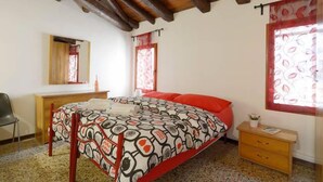 Ein Schlafzimmer mit einem Bett, einem Holztisch, einem Stuhl und einem Fenster mit Vorhängen.