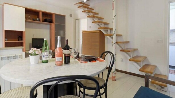 Ein Essbereich mit einem runden Tisch, Stühlen und einer Treppe mit Holzstufen.