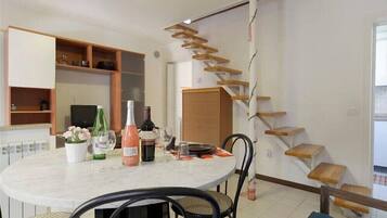 A dining area with a round table, chairs, and a staircase with wooden steps.