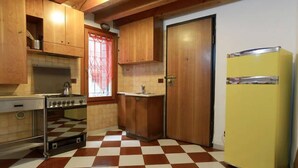 A kitchen with wooden cabinets, a checkered floor, a yellow refrigerator, and a door. - Mario Apartment 1479 (Venice)