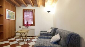 A room with a checkered floor, a sofa, a table, and a radiator. - Mario Apartment 1479 (Venice)