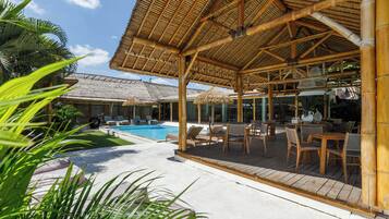 Uma área externa coberta com piscina, espreguiçadeiras e uma mesa.