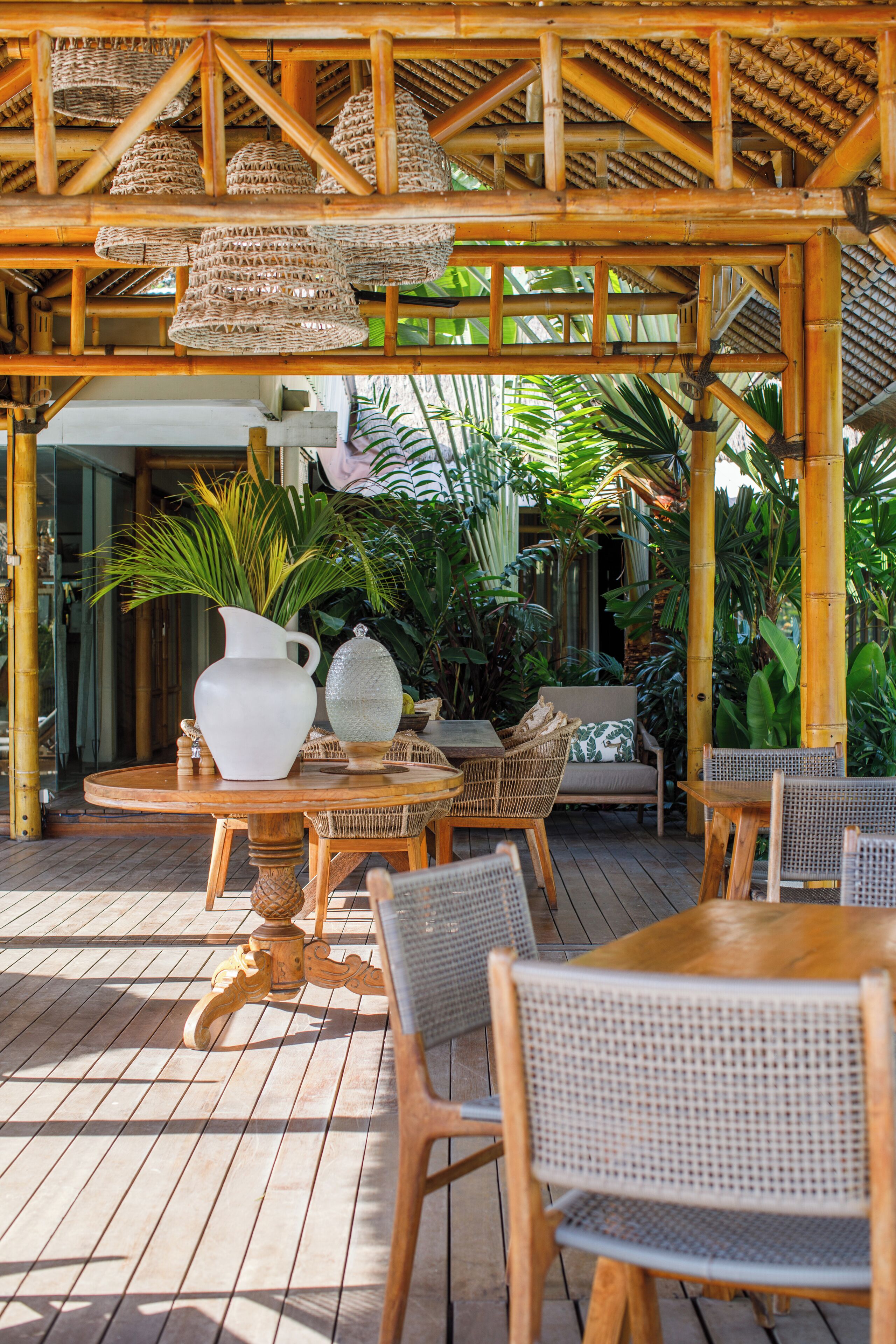 An outdoor patio with wooden furniture, a white pitcher, and decorative items.