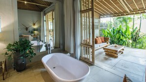 A bathroom with a freestanding bathtub, a large mirror, and a potted plant. - Bloomfield Umalas (Kerobokan)