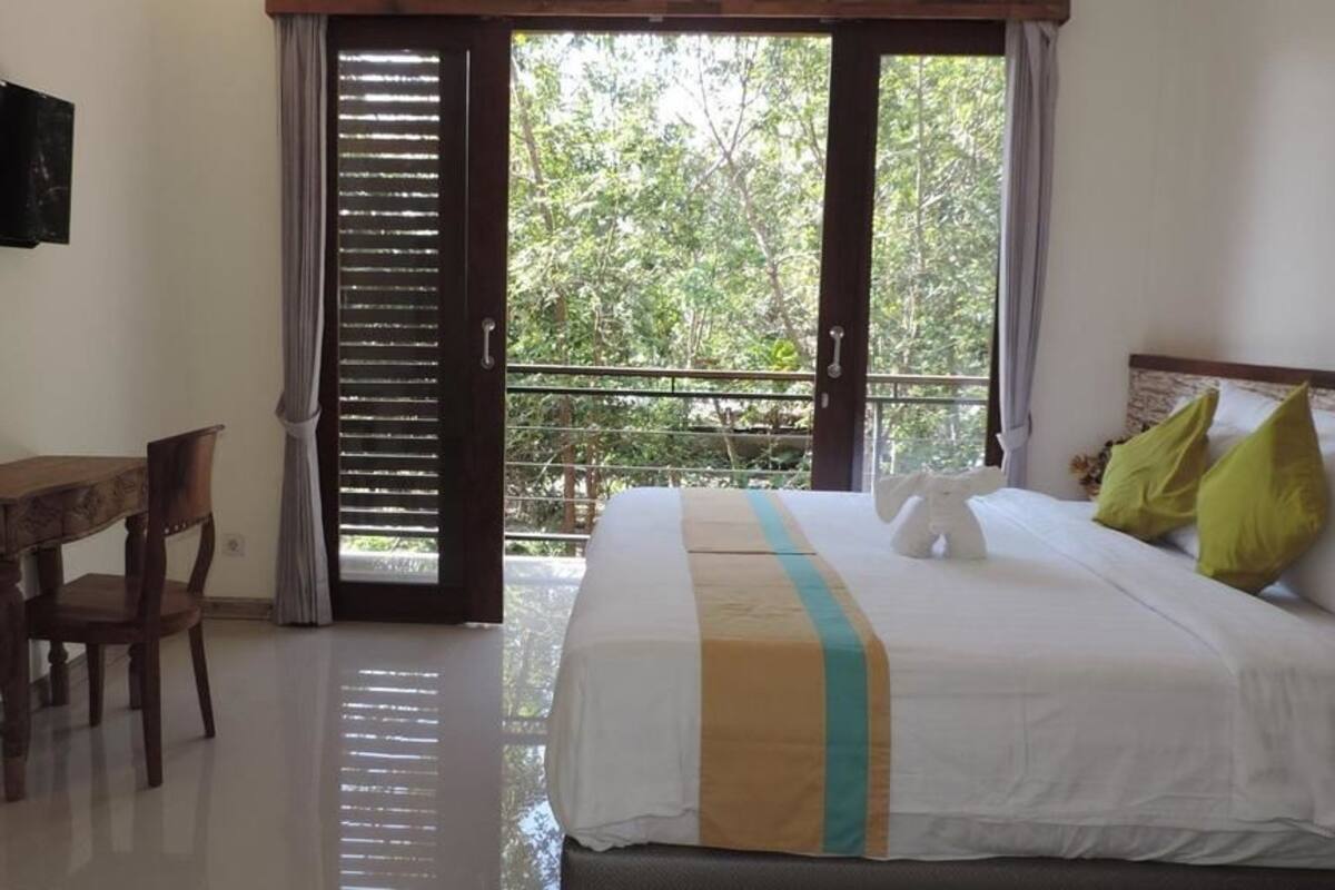 Un dormitorio con cama, escritorio y televisor en la pared.