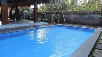 Una piscina al aire libre, sillones reclinables de piscina