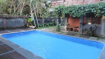 Una piscina al aire libre, sillones reclinables de piscina