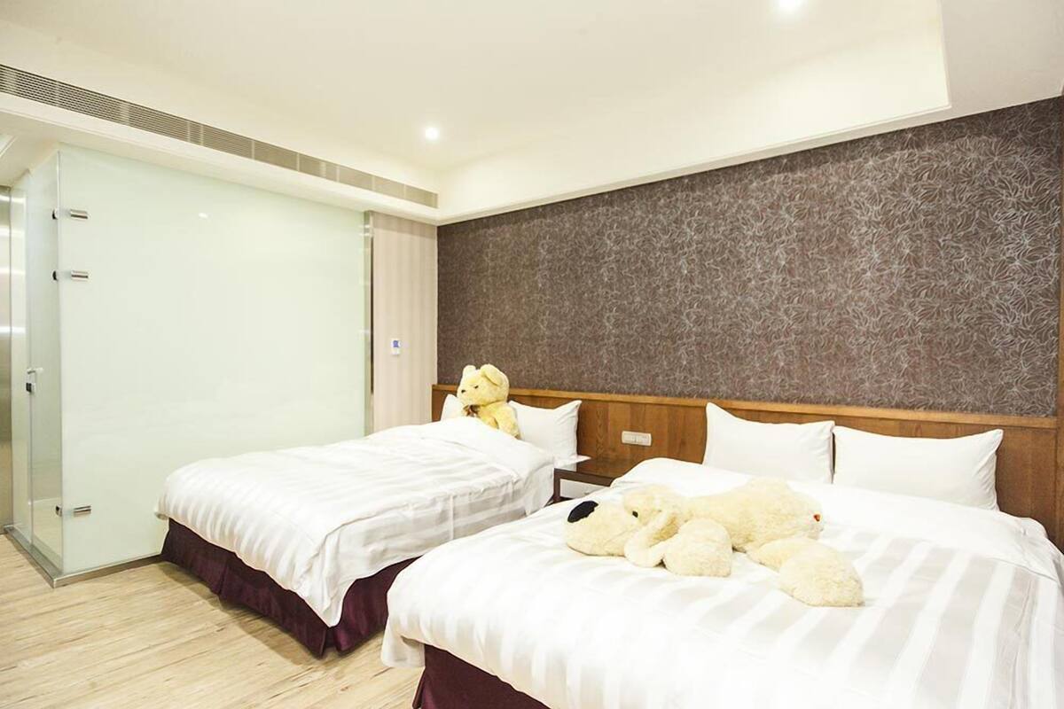 A hotel room with two beds, a wooden headboard, and a glass door closet.