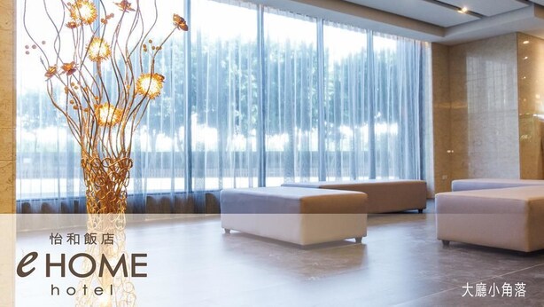 A modern hotel lobby with large windows, a decorative plant, and comfortable seating areas.