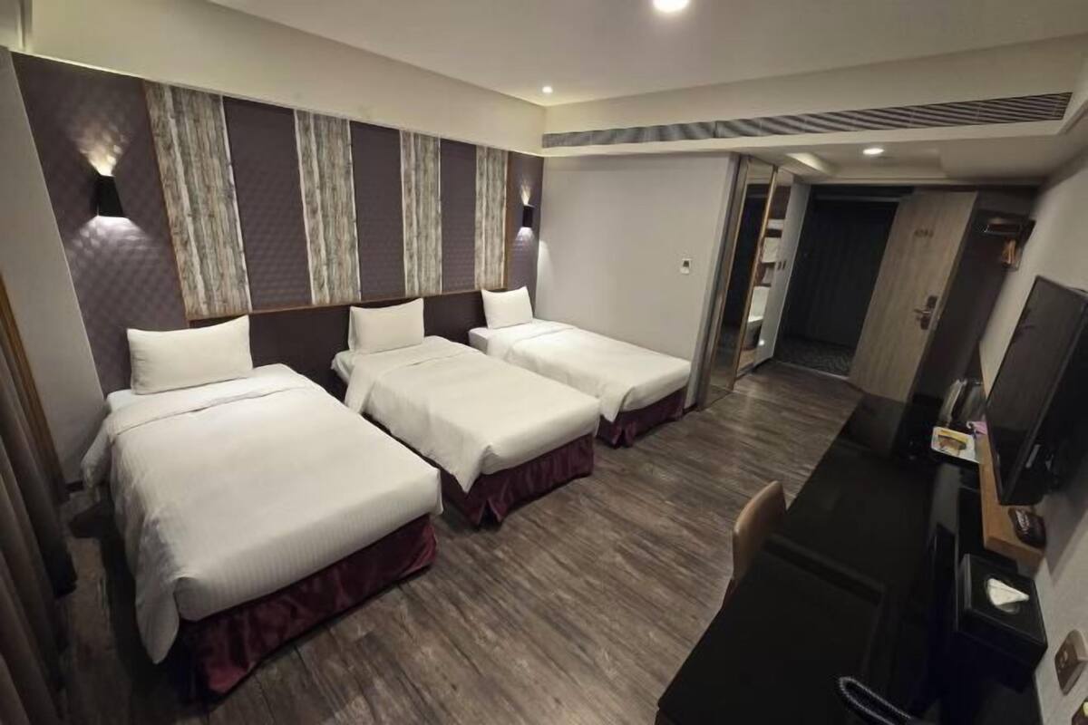 A hotel room with two beds, a desk, and a mirror.