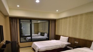 A hotel room with two beds, a large window, a television, and a desk.