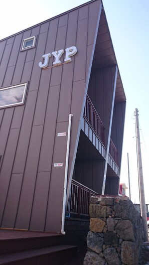 Un bâtiment orné d’une enseigne « JYP », d’une indication de présence de caméras de surveillance et d’un pilier en pierre.