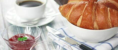 Un tavolo con croissant, una tazza di caffè e due piccole ciotole di marmellata.