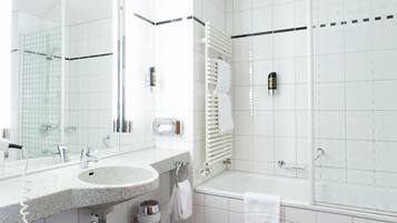 A modern bathroom with a large mirror, a sink, a bathtub, and a toilet.