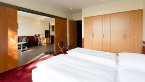 Une chambre d’hôtel dotée d’un grand lit, d’une armoire en bois et d’un coin salon avec une table et des chaises.