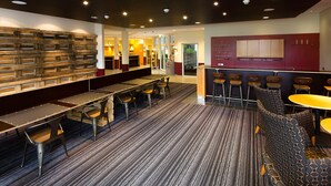 Un espace bar moderne, doté de sièges et d’un tapis à motifs.