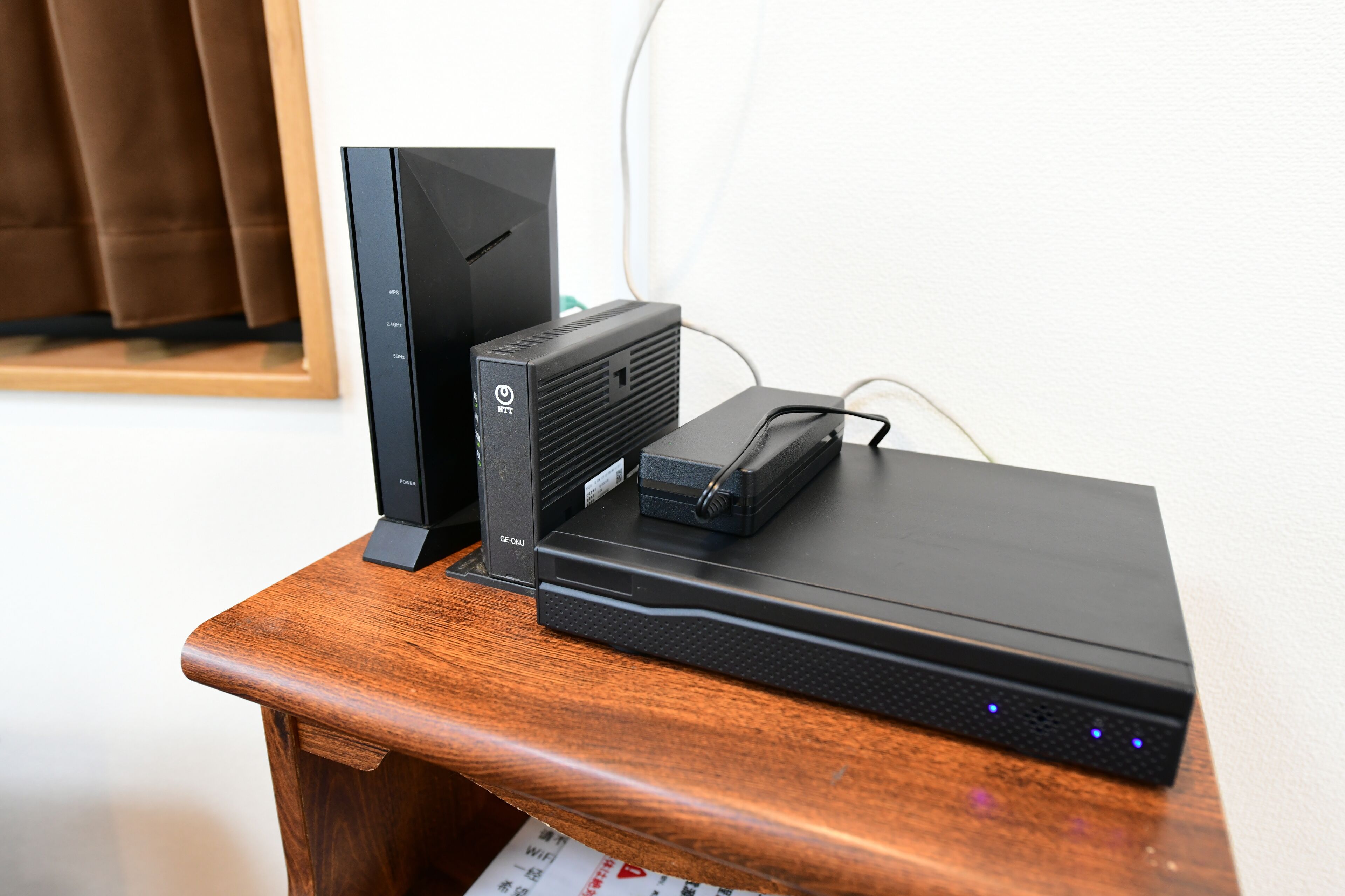 Un escritorio de madera con un dispositivo electrónico negro, posiblemente una consola de videojuegos, y un monitor.