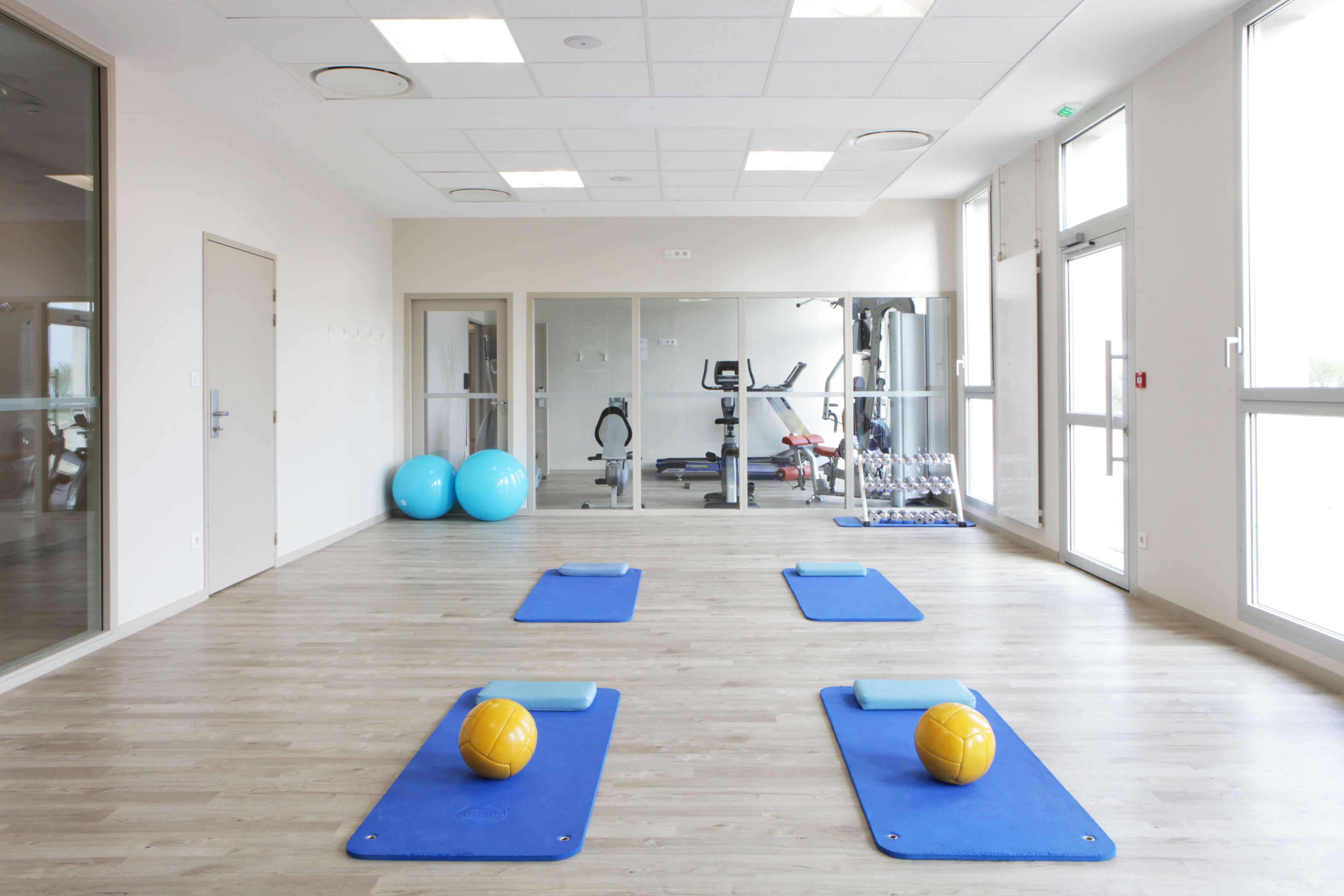 Un gimnasio amplio con colchonetas de ejercicio, balones y equipamiento de fitness.