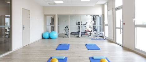 Un gimnasio amplio con colchonetas de ejercicio, balones y equipamiento de fitness.