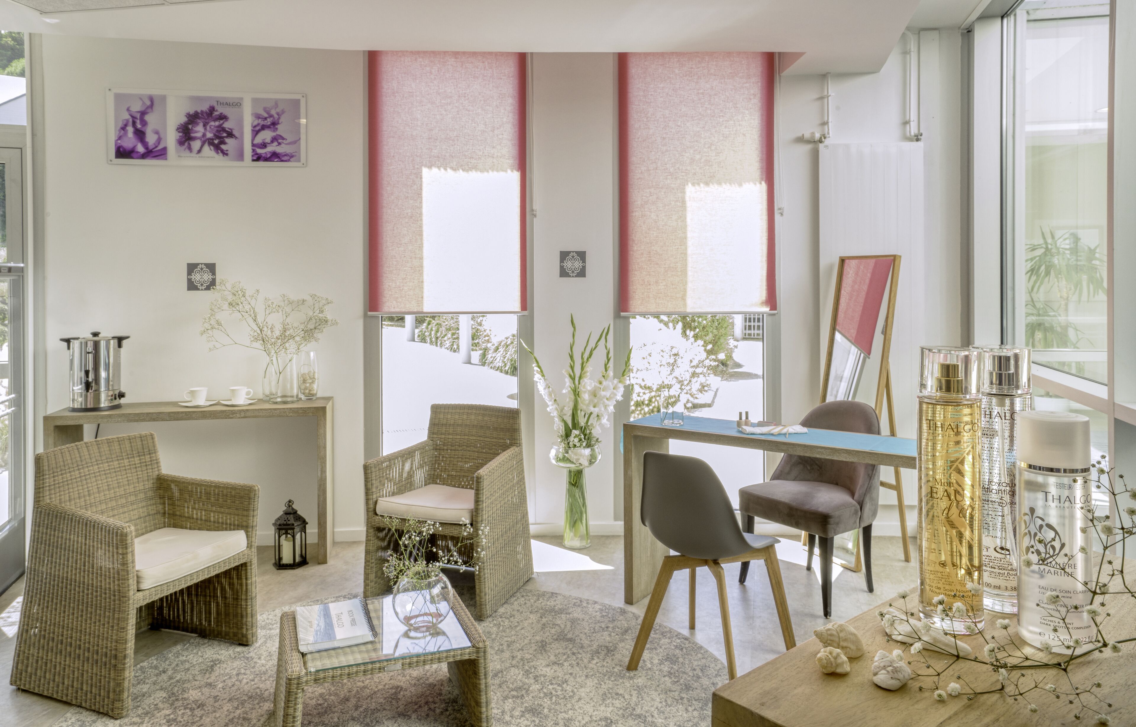 A modern living room with wicker furniture, a coffee table, and a desk with chairs. There are decorative items like vases and a mirror.