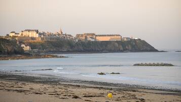 A coastal town with historic buildings, a beach, and a lighthouse.