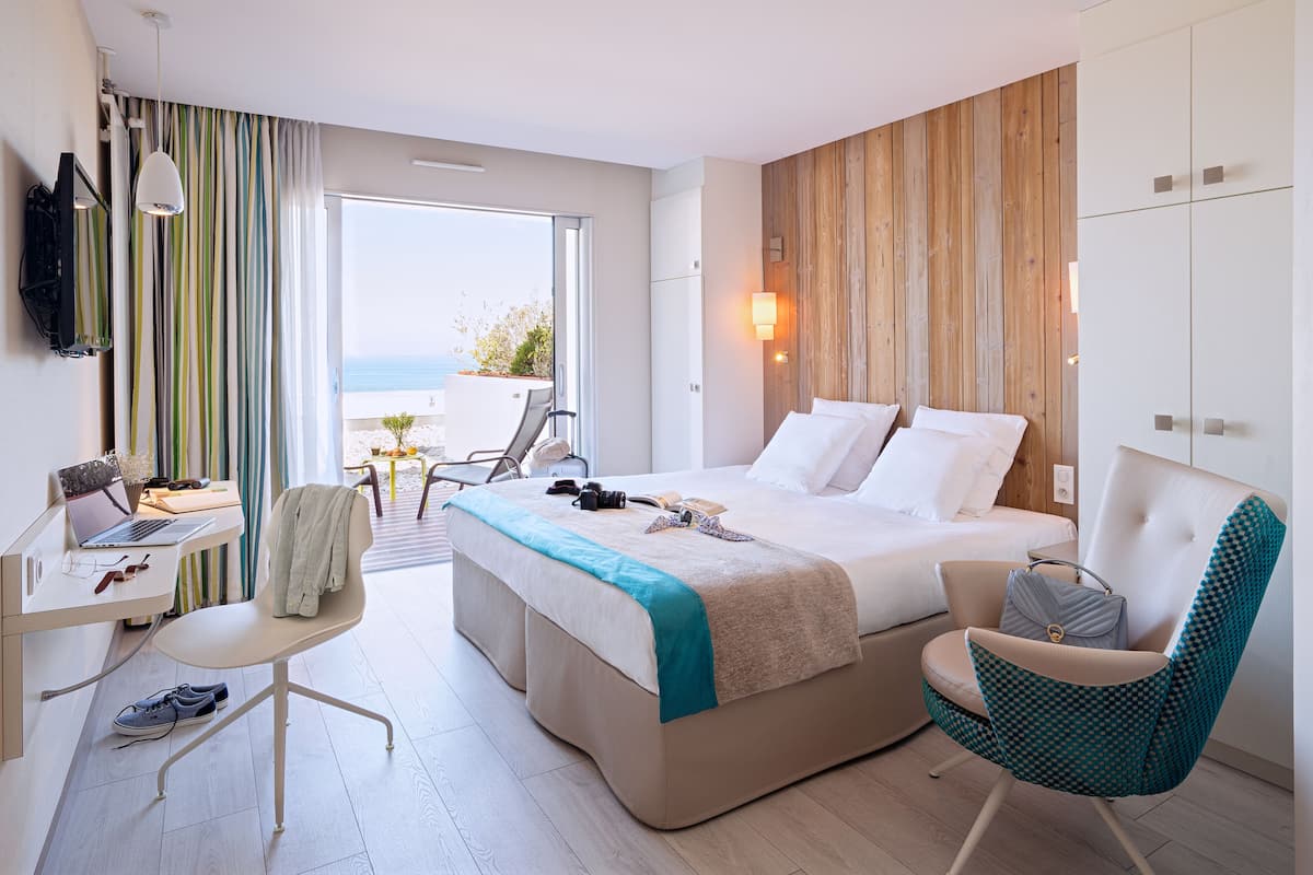 Une chambre d’hôtel moderne équipée d’un lit, d’un bureau, d’une chaise et offrant une vue sur la mer.