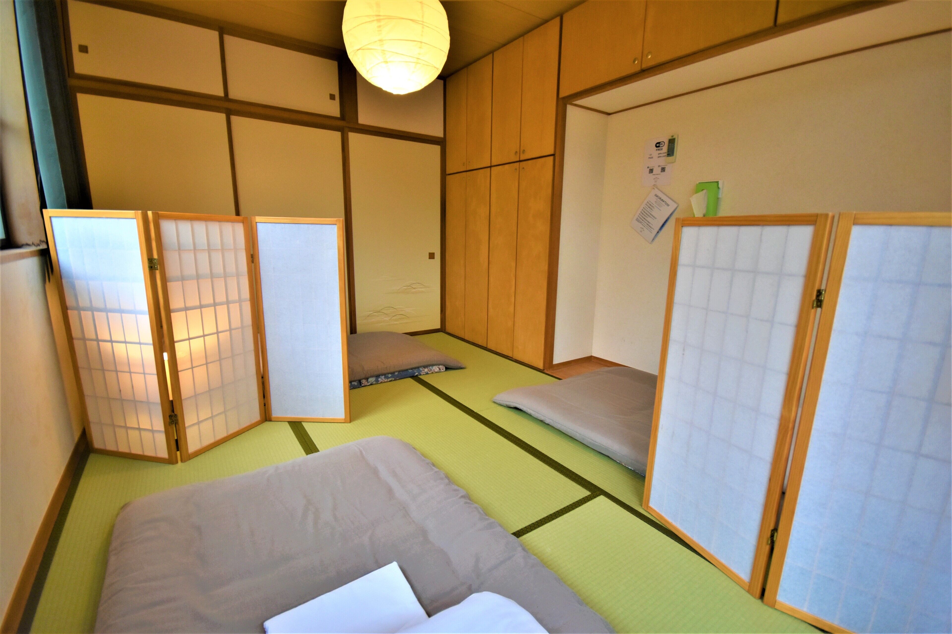 Una habitación de estilo japonés tradicional, con suelo de tatami, una cama baja y puertas correderas.