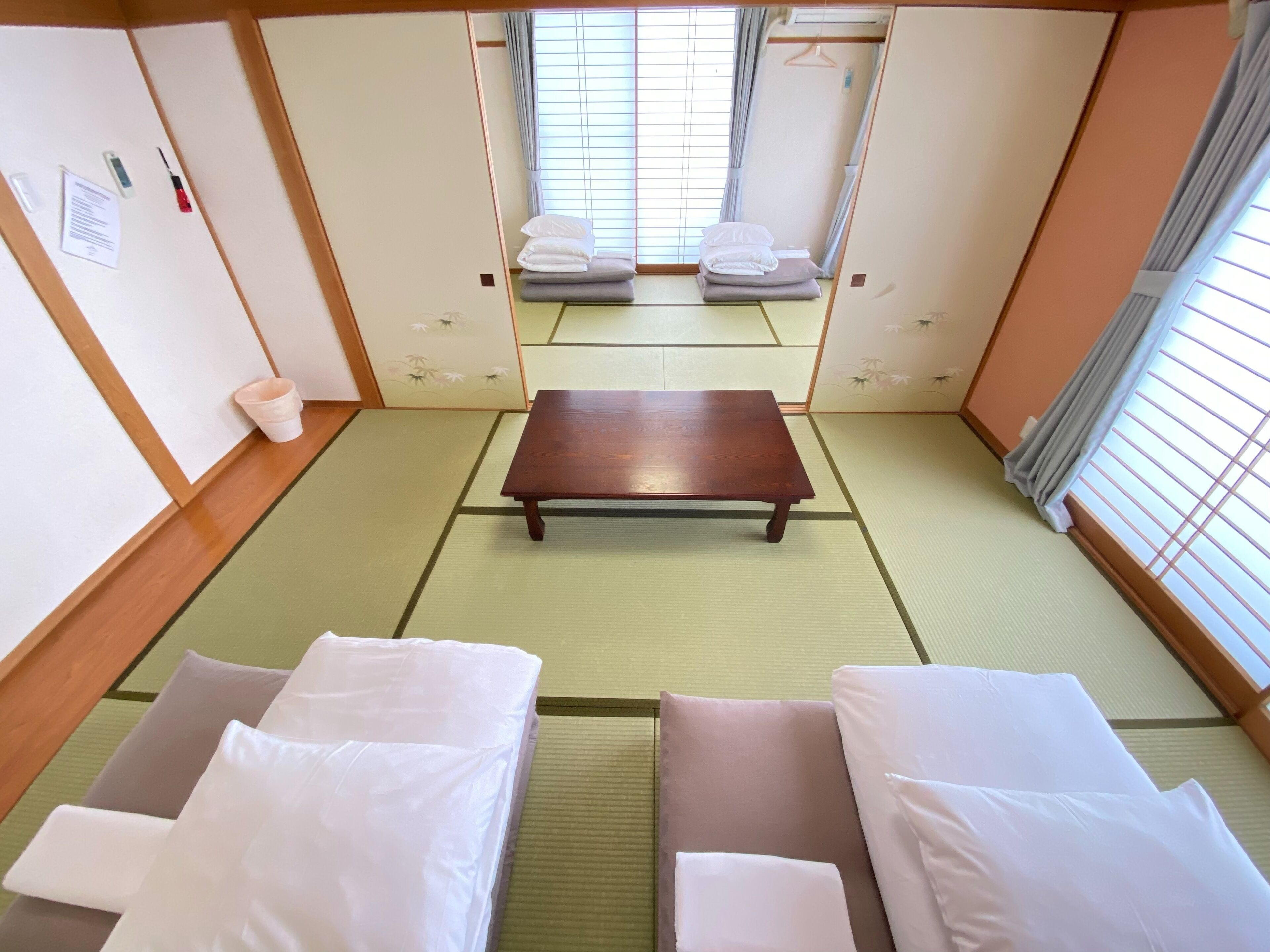 A traditional Japanese-style room with tatami flooring, a low wooden table, and two tatami mats with pillows.