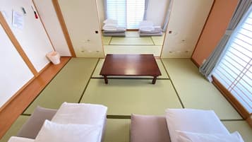 A traditional Japanese-style room with tatami flooring, a low wooden table, and two tatami mats with pillows.