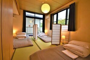 A traditional Japanese-style hotel room with tatami flooring, a shoji screen, and a view of the outdoors. - Hakone Guesthouse Gaku - Hostel (Hakone)