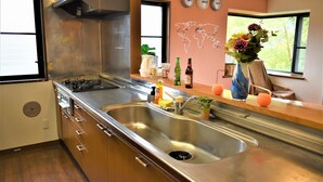 A modern kitchen with stainless steel appliances, a double sink, and a world map decoration on the wall.
