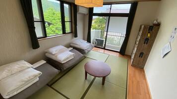 A room with tatami mats, a low table, and a sofa with pillows.