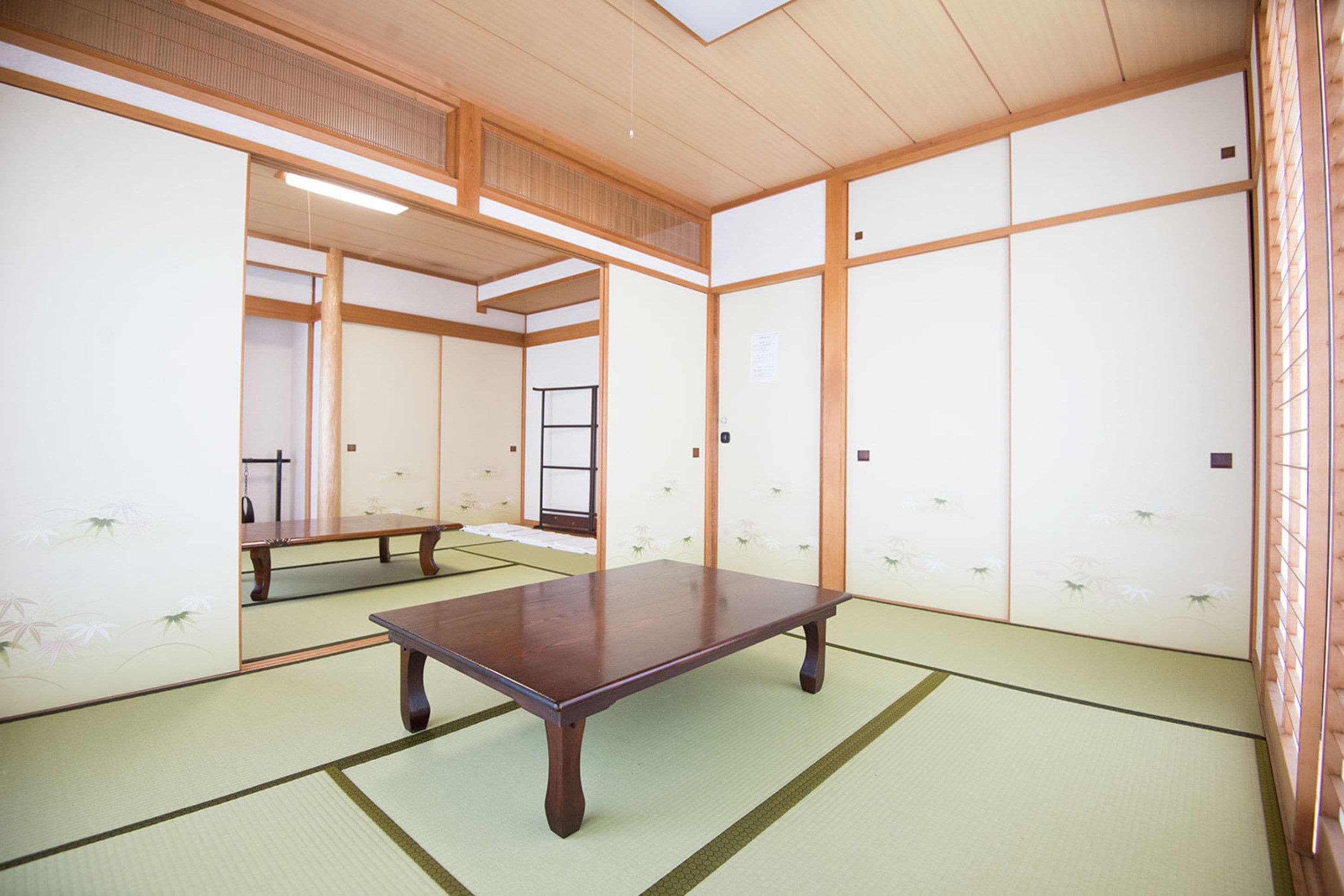 A traditional Japanese room with tatami flooring, a low wooden table, sliding doors, and a shoji screen.