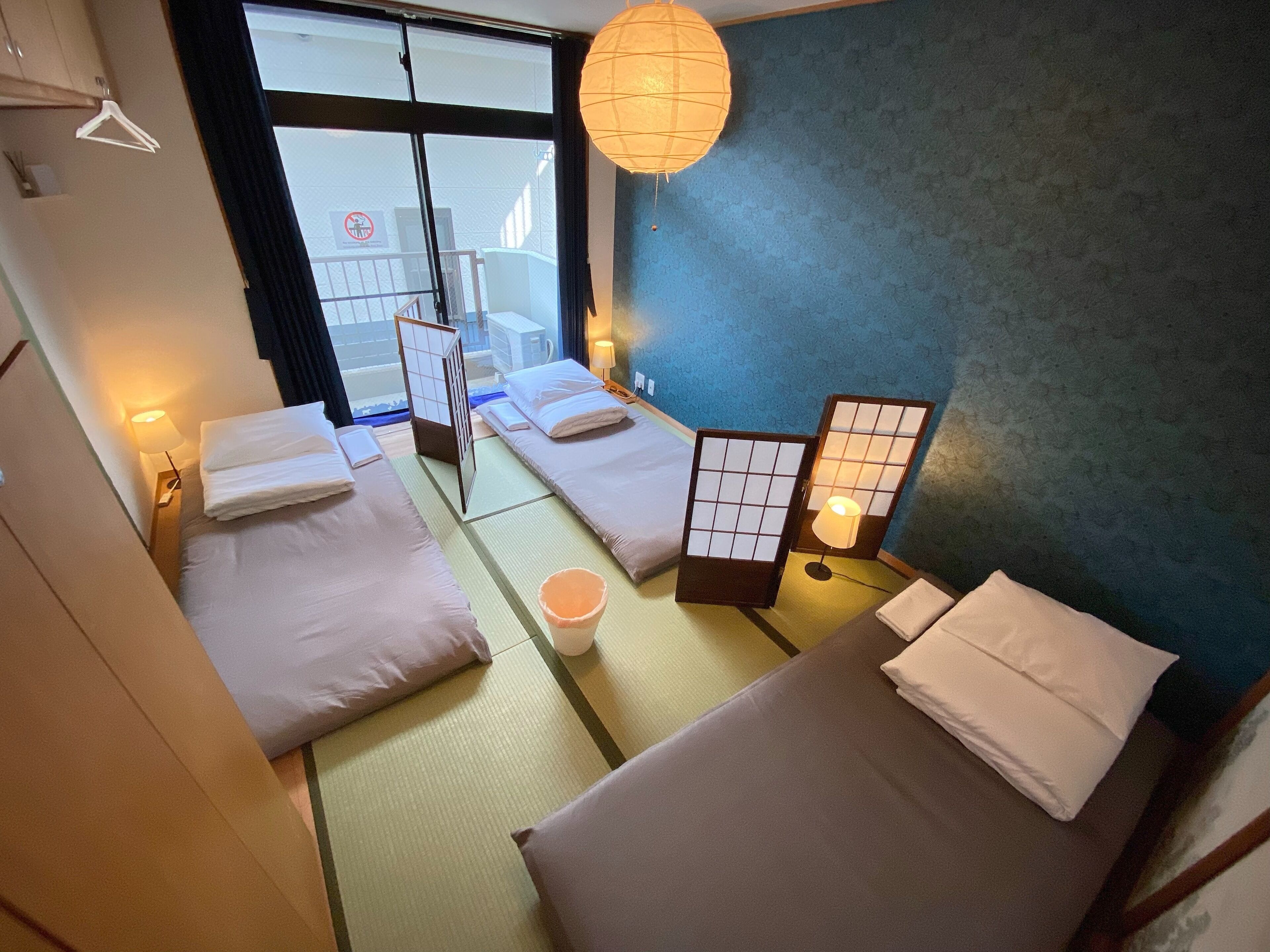 A traditional Japanese-style hotel room with tatami mats, shoji screens, and a view of the outside.