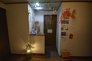 A reception area with a desk, a sign indicating 'House Rules', a fire extinguisher, and a small plant.
