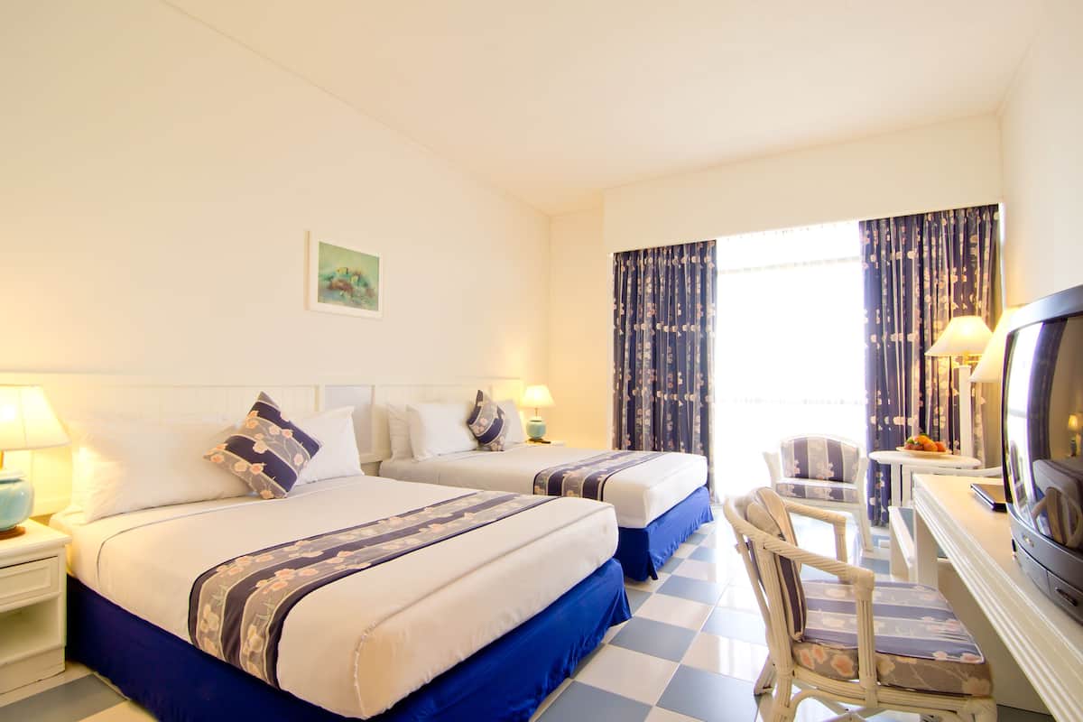 Une chambre d’hôtel avec deux lits, un bureau avec une télévision et une chaise.