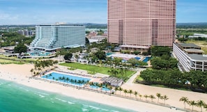 Un resort costero con un hotel grande, una piscina y una playa.
